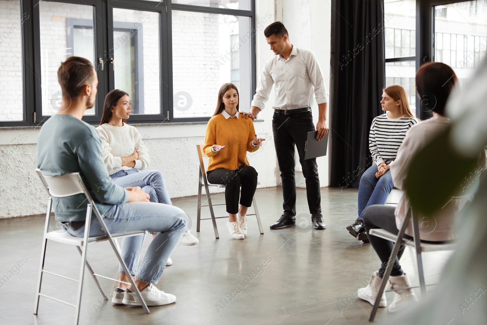 Photo of Psychotherapist working with patients in group therapy session indoors