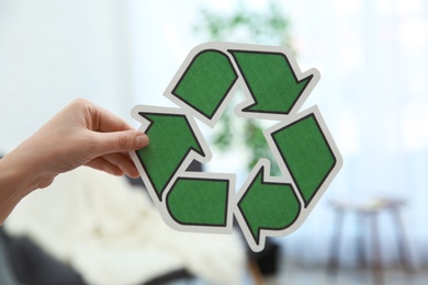 Photo of Woman holding recycling symbol on blurred background, closeup