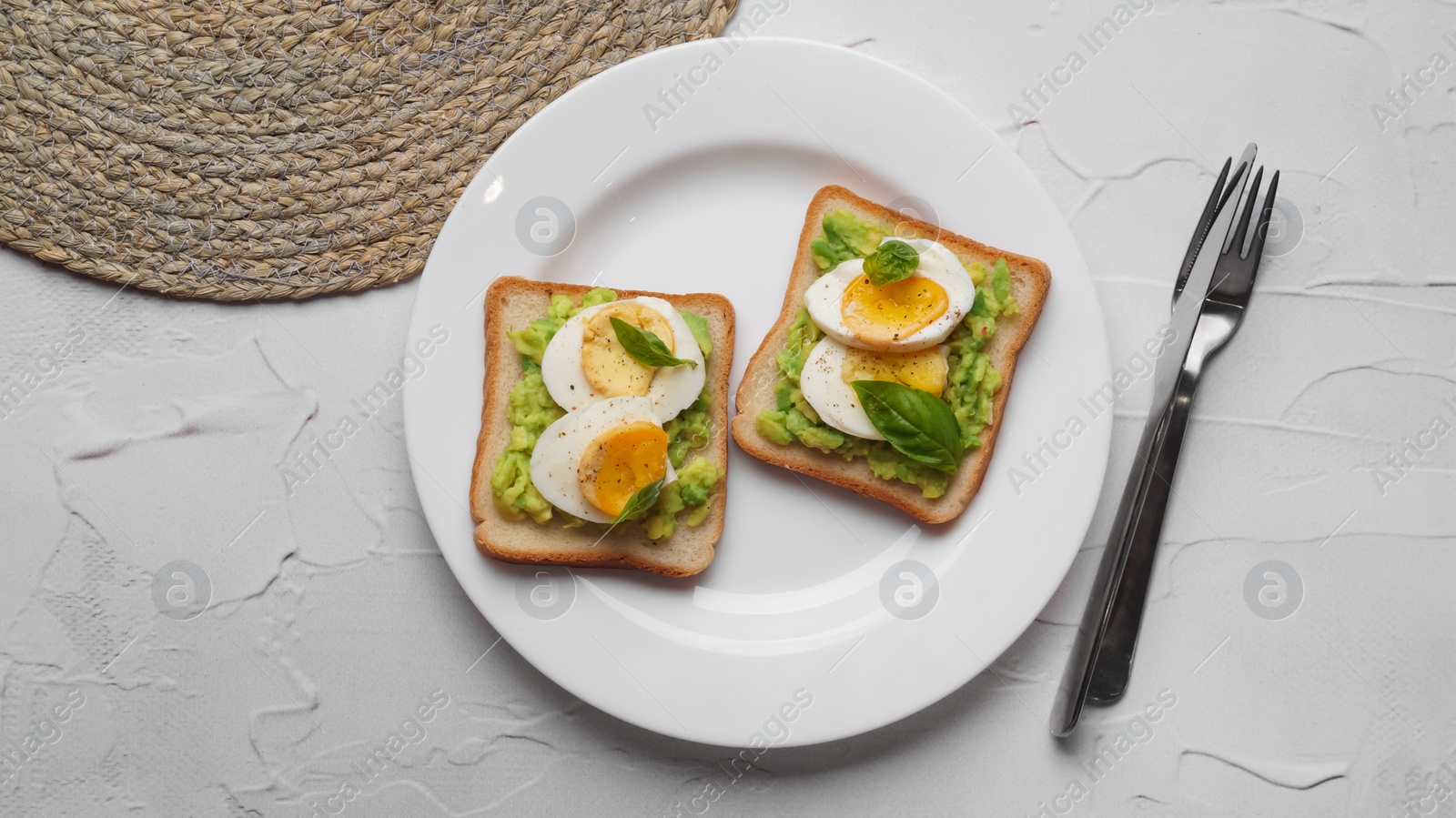 Photo of Tasty sandwiches with boiled egg, avocado and spinach served on white textured table, flat lay