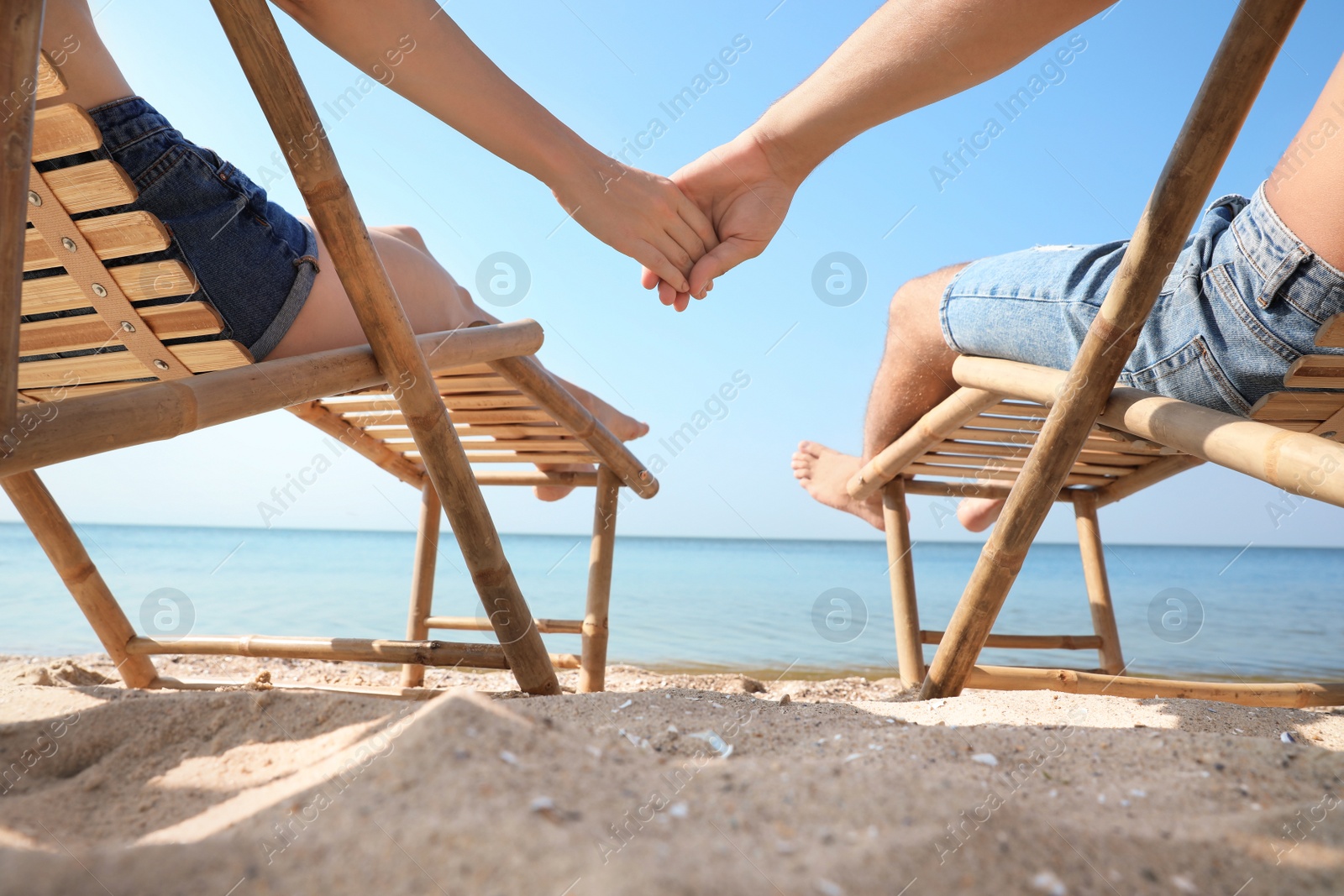 Photo of Young couple relaxing in deck chairs on beach near sea, closeup