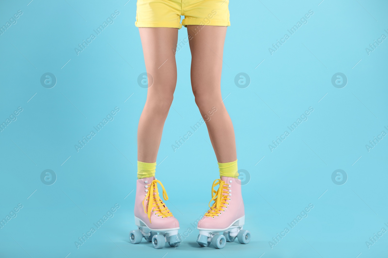 Photo of Young woman with retro roller skates on color background, closeup