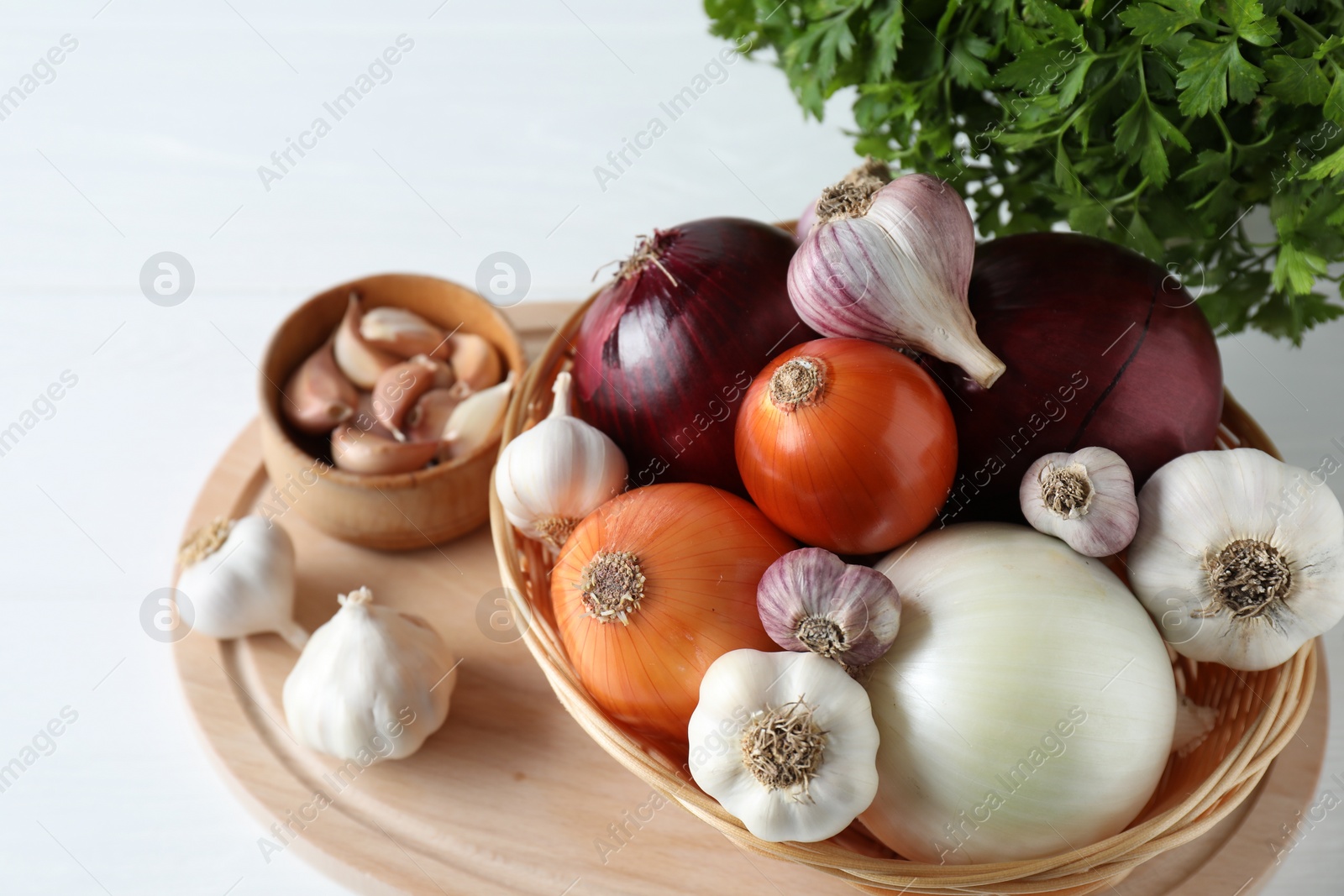 Photo of Fresh raw garlic, onions and parsley on white table, above view