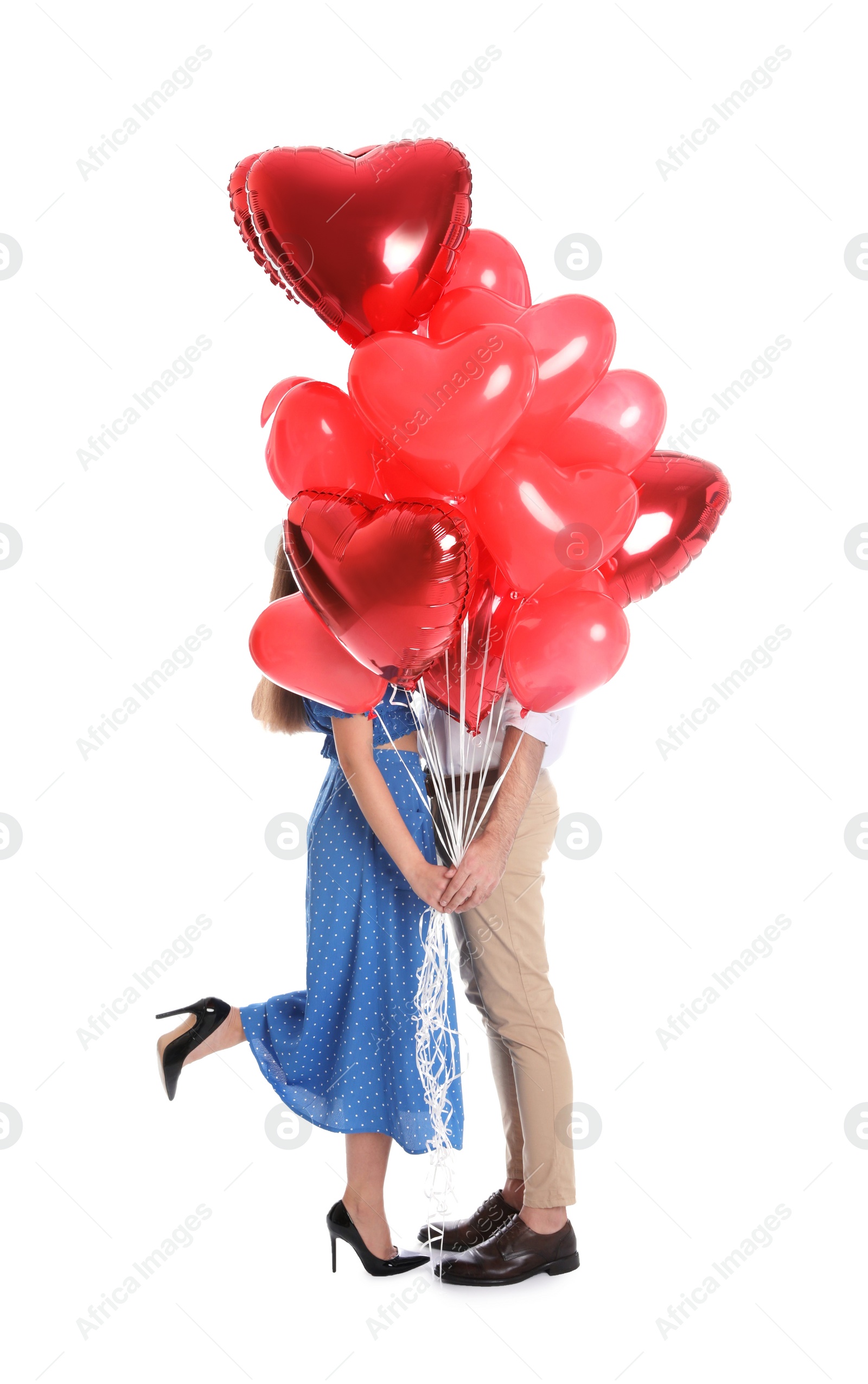 Photo of Young couple hiding behind heart shaped balloons isolated on white. Valentine's day celebration