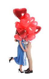 Photo of Young couple hiding behind heart shaped balloons isolated on white. Valentine's day celebration