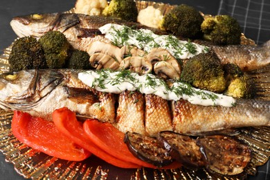 Photo of Delicious baked sea bass fish with sauce on plate, closeup