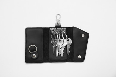 Photo of Open leather holder with keys on light grey background, top view
