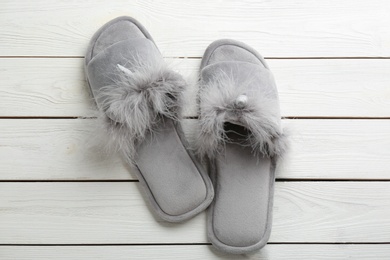 Photo of Pair of stylish soft slippers on white wooden background, flat lay