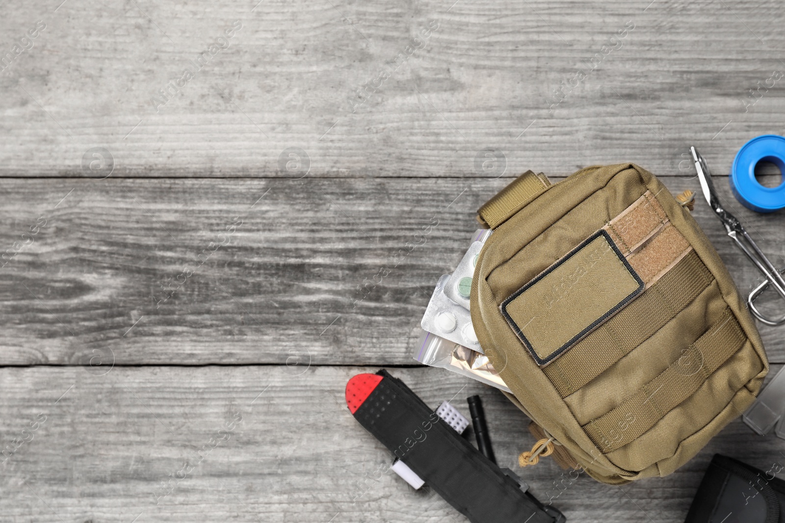 Photo of Military first aid kit on wooden table, flat lay. Space for text