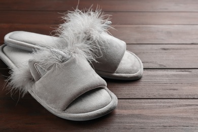 Photo of Pair of stylish soft slippers on wooden background
