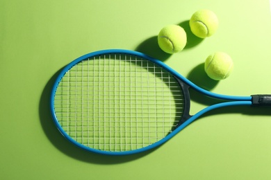 Photo of Tennis racket and balls on green background, flat lay. Sports equipment