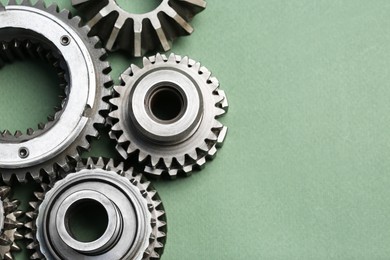 Photo of Different stainless steel gears on light green background, above view. Space for text