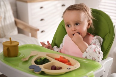 Photo of Cute little baby wearing bib while eating at home