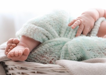 Photo of Cute newborn baby lying on plaid in basket at home