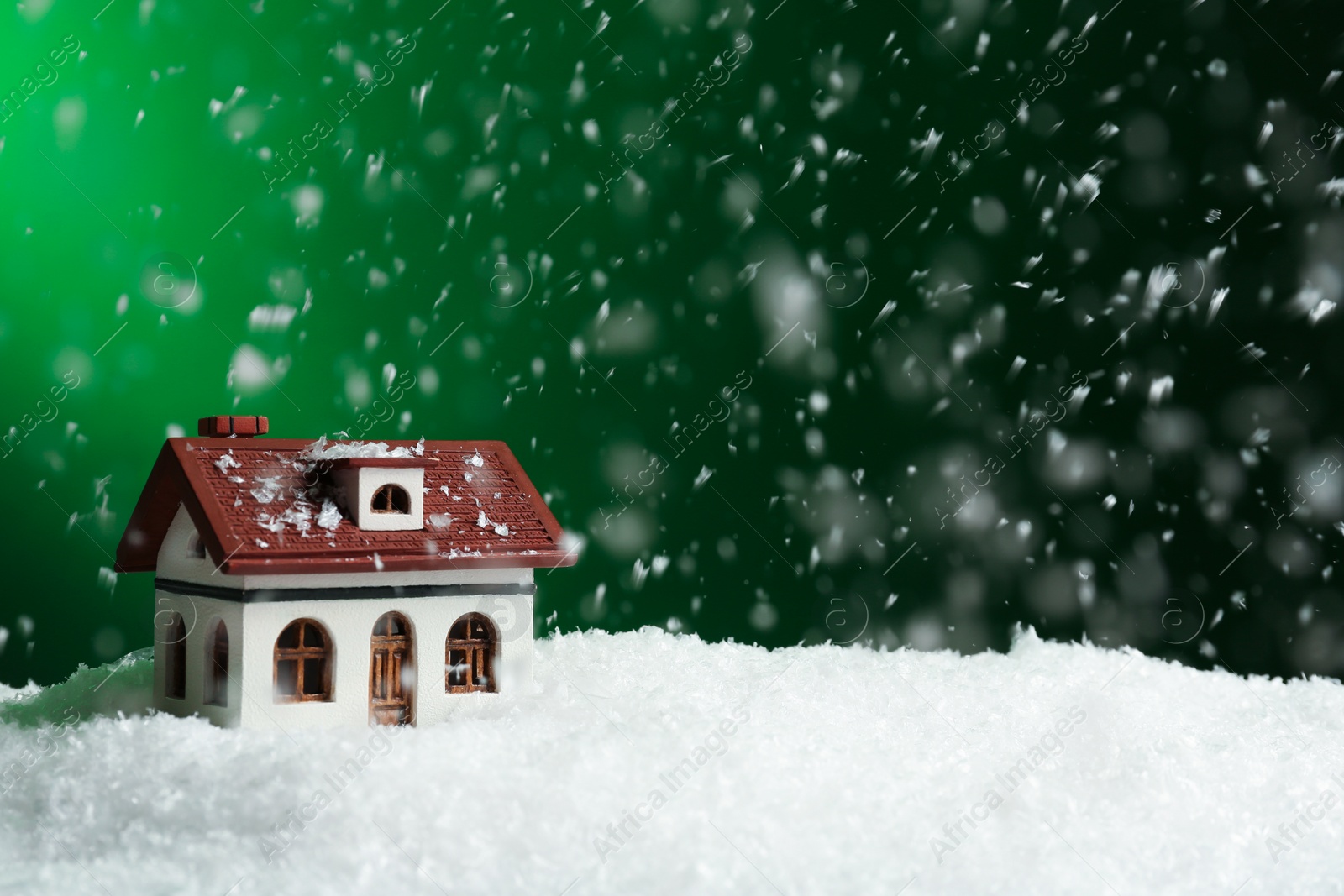 Photo of Decorative house in snowdrift on color background, space for text. Winter weather