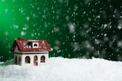 Decorative house in snowdrift on color background, space for text. Winter weather