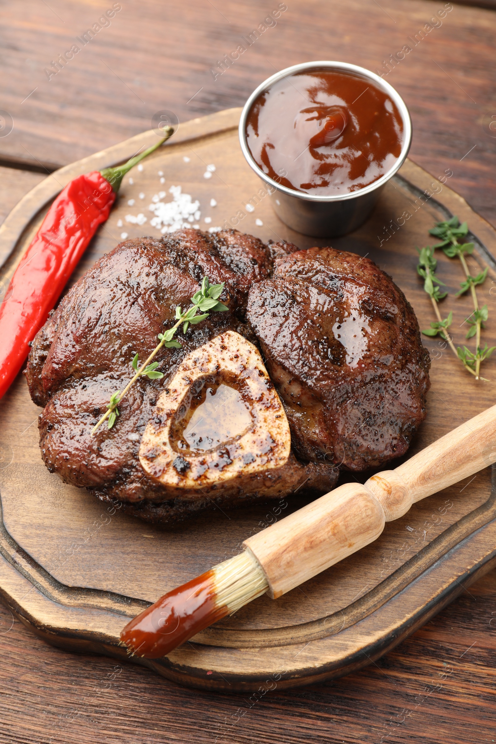 Photo of Delicious roasted beef meat served with sauce and spices on wooden table, closeup