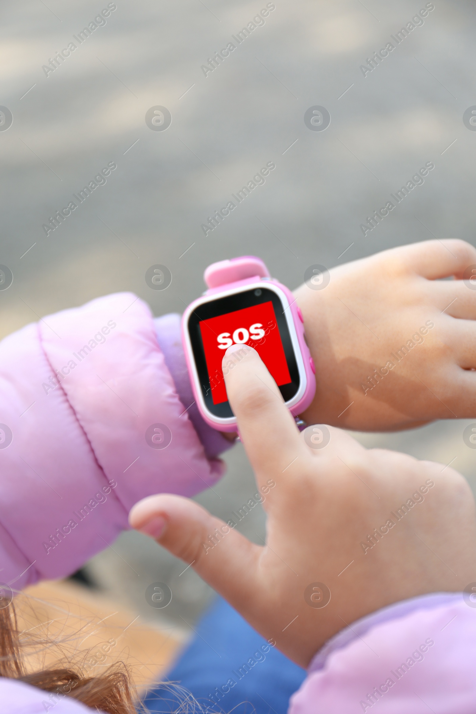Image of Little girl using SOS function on smartwatch outdoors, closeup