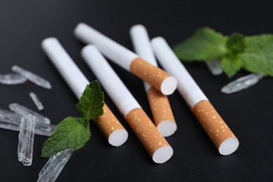 Cigarettes, menthol crystals and mint on black background, closeup