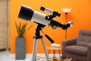 Tripod with modern telescope in stylish room, closeup