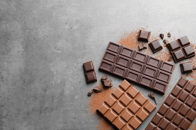 Different kinds of chocolate on grey background, flat lay. Space for text