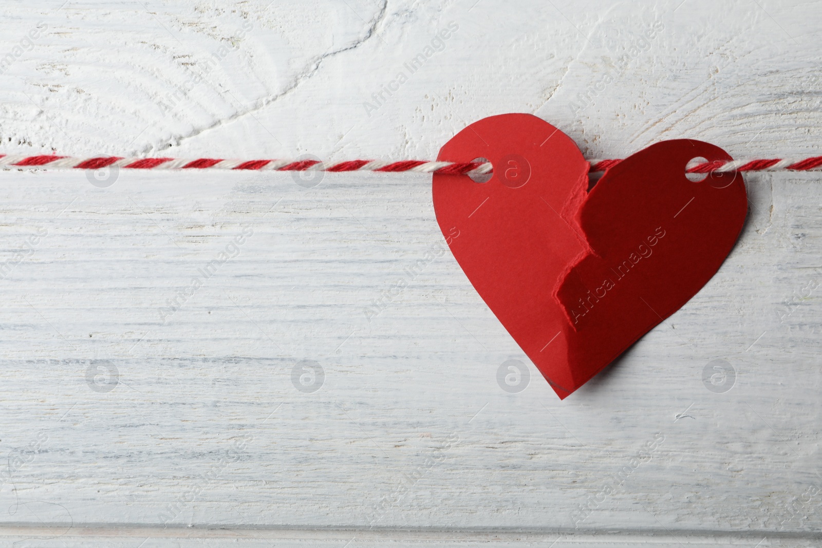 Photo of Broken red paper heart and rope on white wooden background. Relationship problems concept