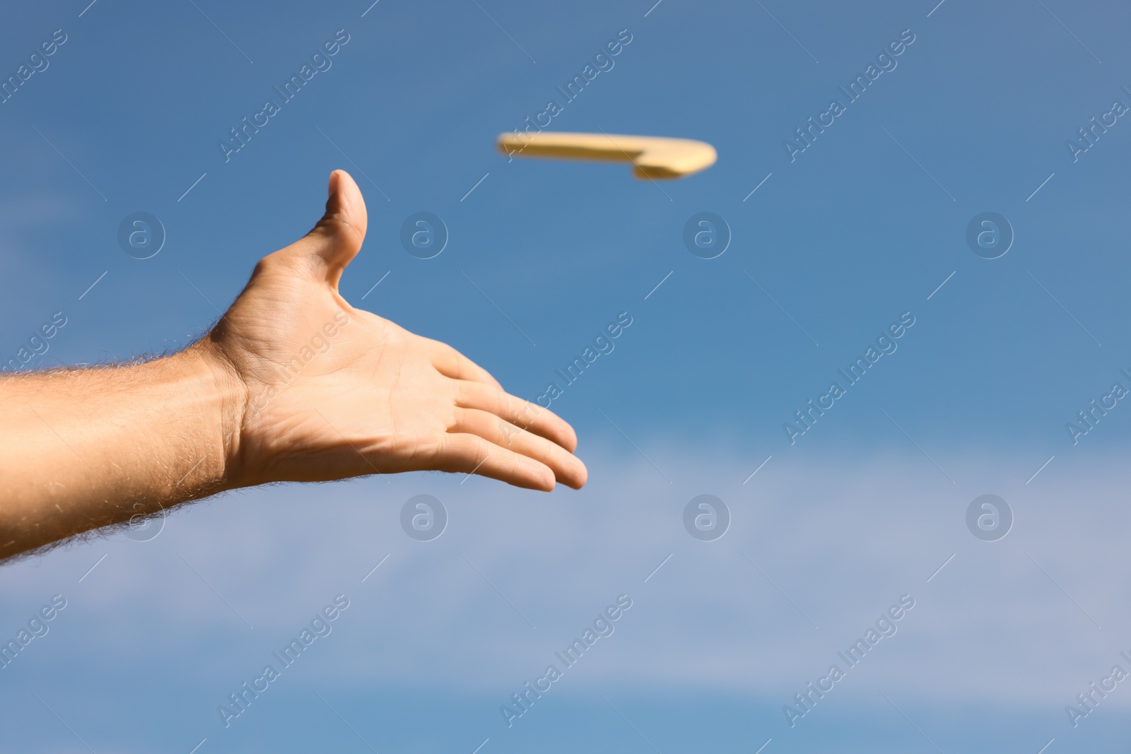 Photo of Man throwing boomerang against blue sky, closeup