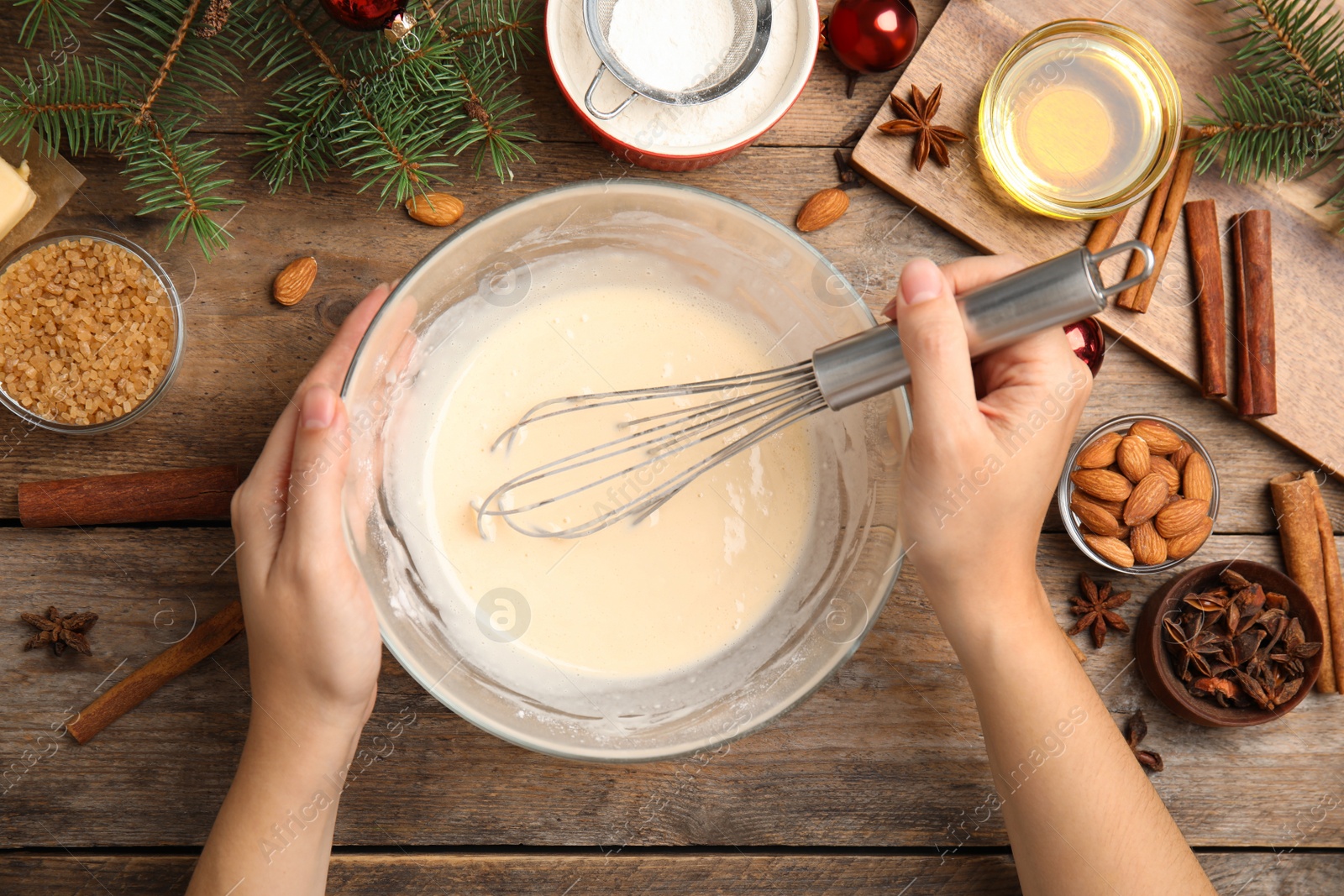 Photo of Woman cooking traditional Christmas cake at wooden table with ingredients, top view