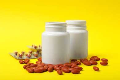 Photo of Bottles with pills on yellow background. Anemia treatment