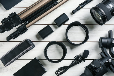 Flat lay composition with camera and video production equipment on white wooden table