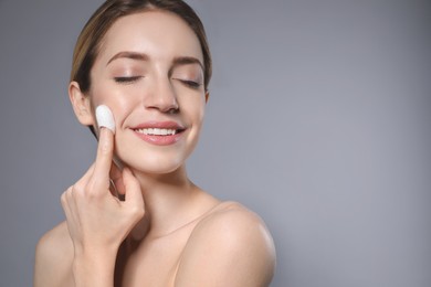 Photo of Woman using silkworm cocoon in skin care routine on grey background. Space for text