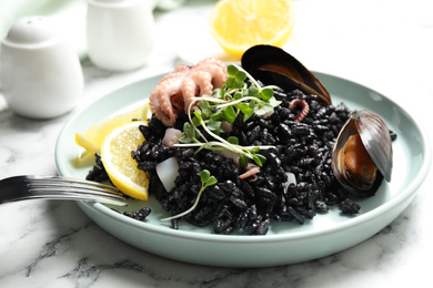 Delicious black risotto with seafood on white marble table