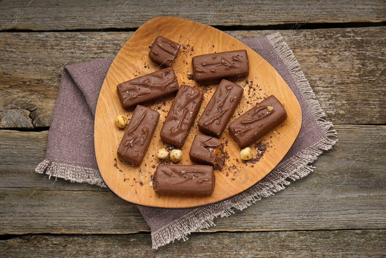 Photo of Delicious chocolate candy bars with nuts on wooden table, top view