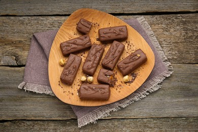 Delicious chocolate candy bars with nuts on wooden table, top view