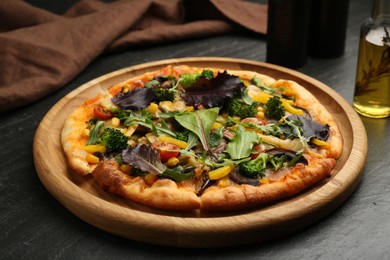 Delicious vegetarian pizza with mushrooms, vegetables and greens on black table