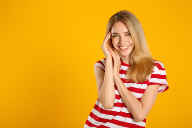 Beautiful young woman with blonde hair on yellow background. Space for text