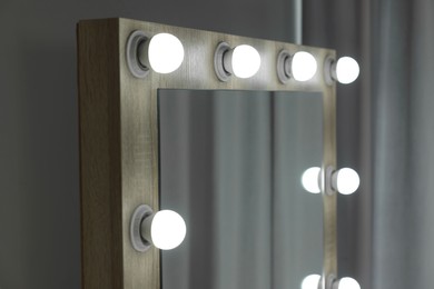 Photo of Beautiful mirror with light bulbs in makeup room, closeup