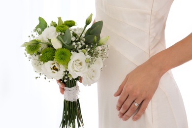 Bride holding beautiful bouquet with Eustoma flowers indoors, closeup