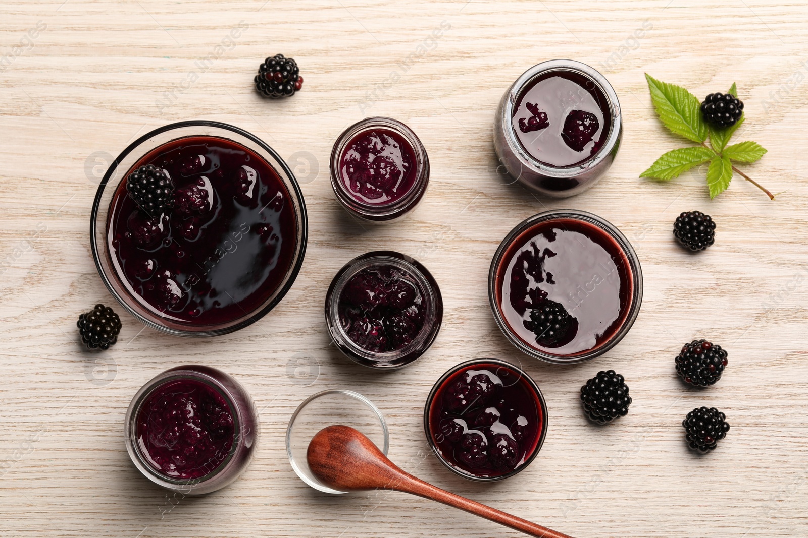Photo of Tasty blackberry jam and fresh berries on white wooden table, flat lay