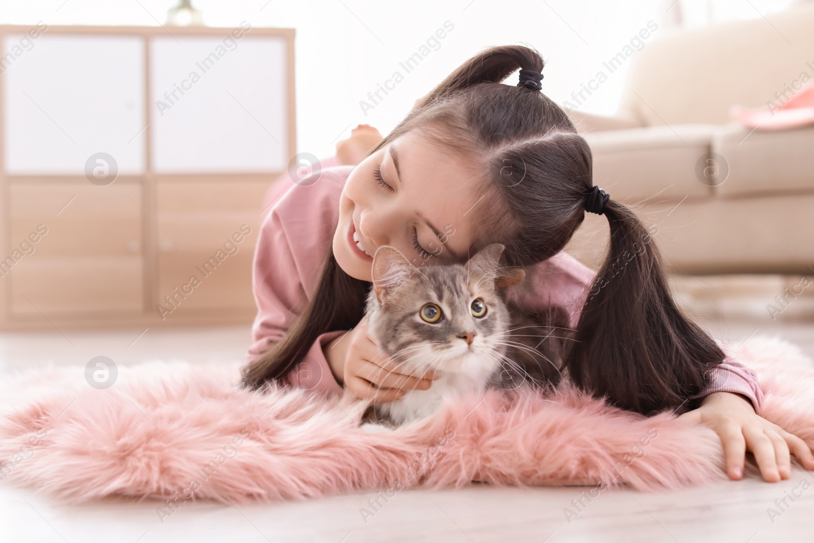 Photo of Cute little girl with cat lying on floor at home