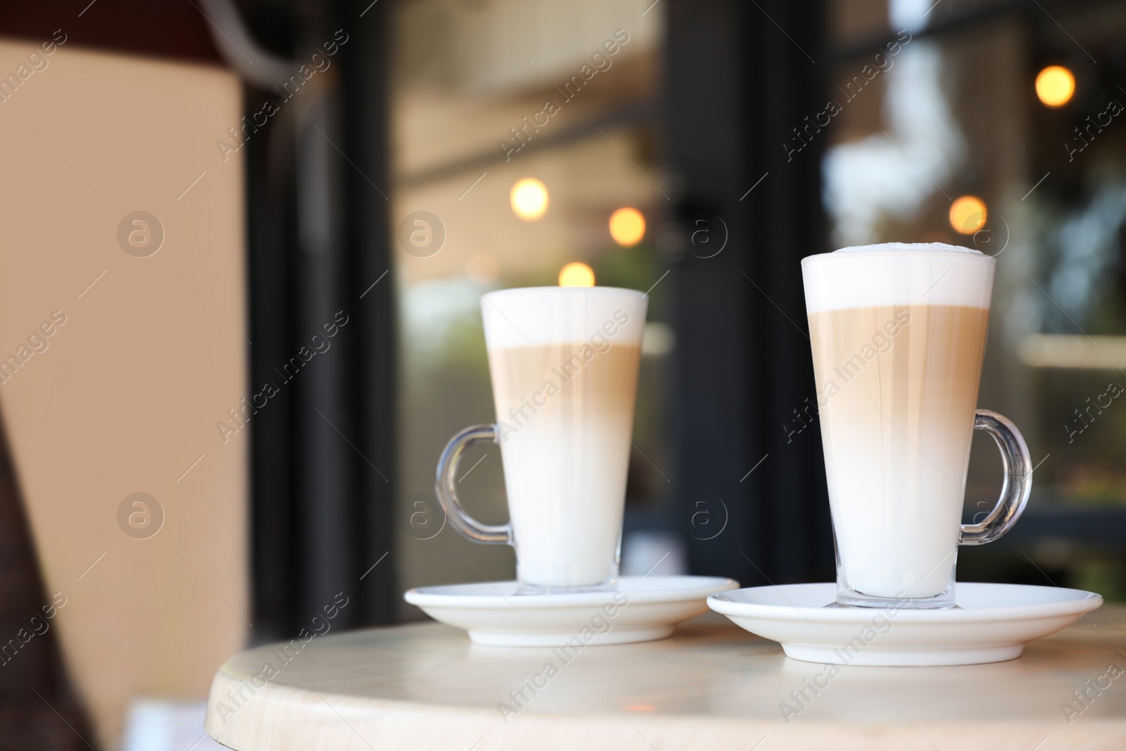 Photo of Glass cups of coffee on table in cafe, space for text