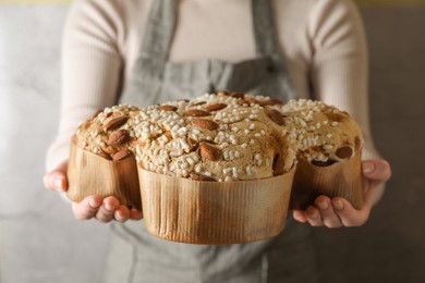 Photo of Woman with delicious Italian Easter dove cake (traditional Colomba di Pasqua) near grey wall, closeup