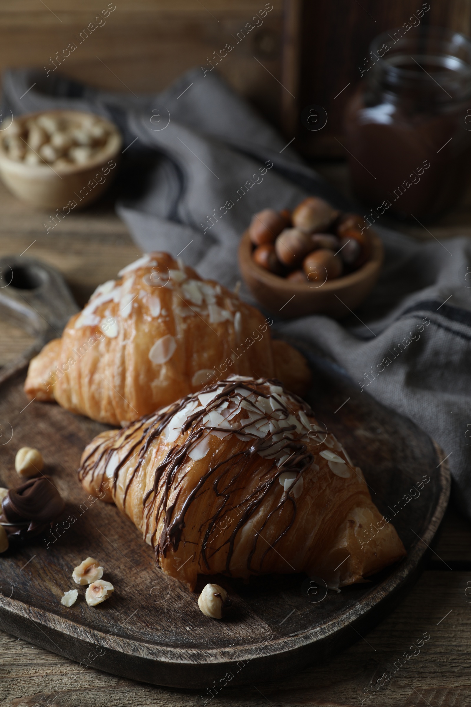 Photo of Delicious croissants with chocolate and nuts on wooden table