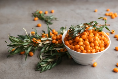 Fresh ripe sea buckthorn in bowl on grey table