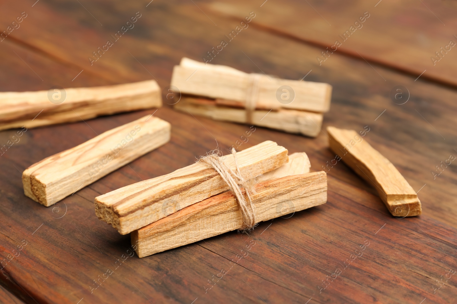 Photo of Bunches of tied Palo Santo sticks on wooden table, closeup