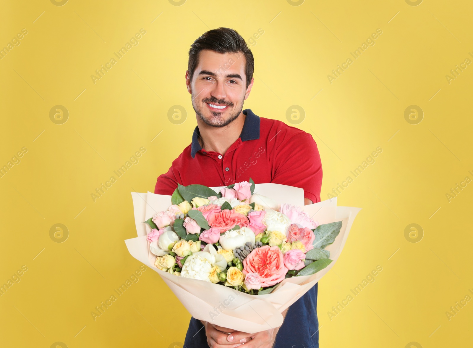 Photo of Young handsome man with beautiful flower bouquet on yellow background