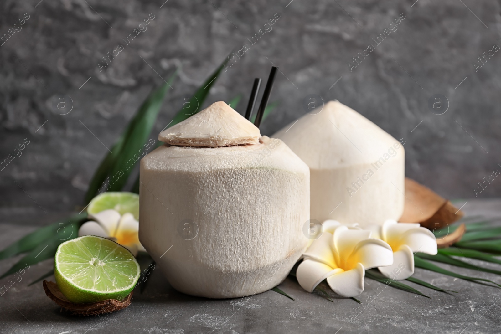 Photo of Composition with fresh coconut drink in nut on grey table