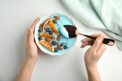 Photo of Woman eating spirulina smoothie at table, top view