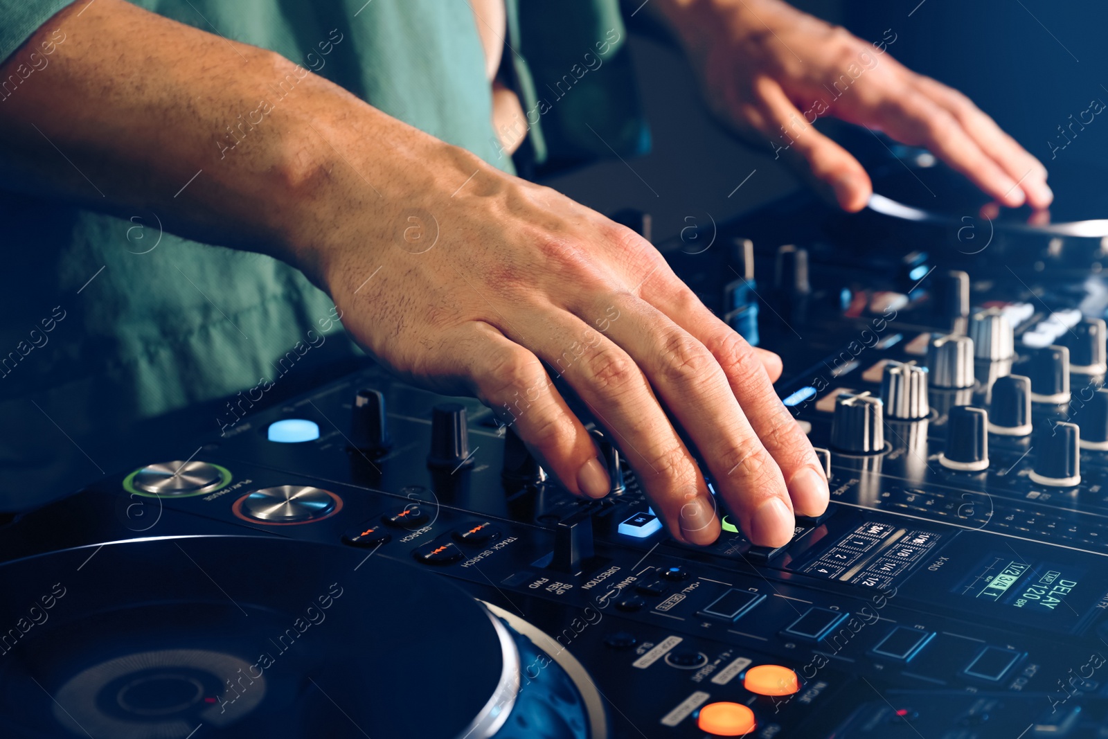 Photo of DJ creating music on modern console mixer in night club, closeup