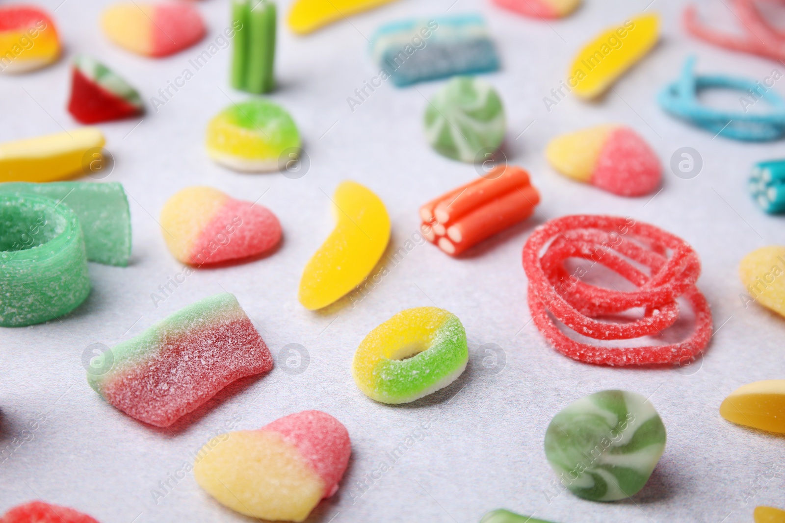 Photo of Many tasty colorful jelly candies on white table, closeup