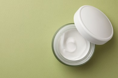 Jar of face cream on light green background, flat lay. Space for text